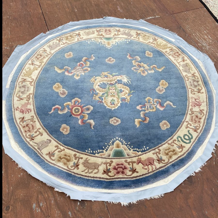 Round Chinese dragon rug with faded pile before shearing